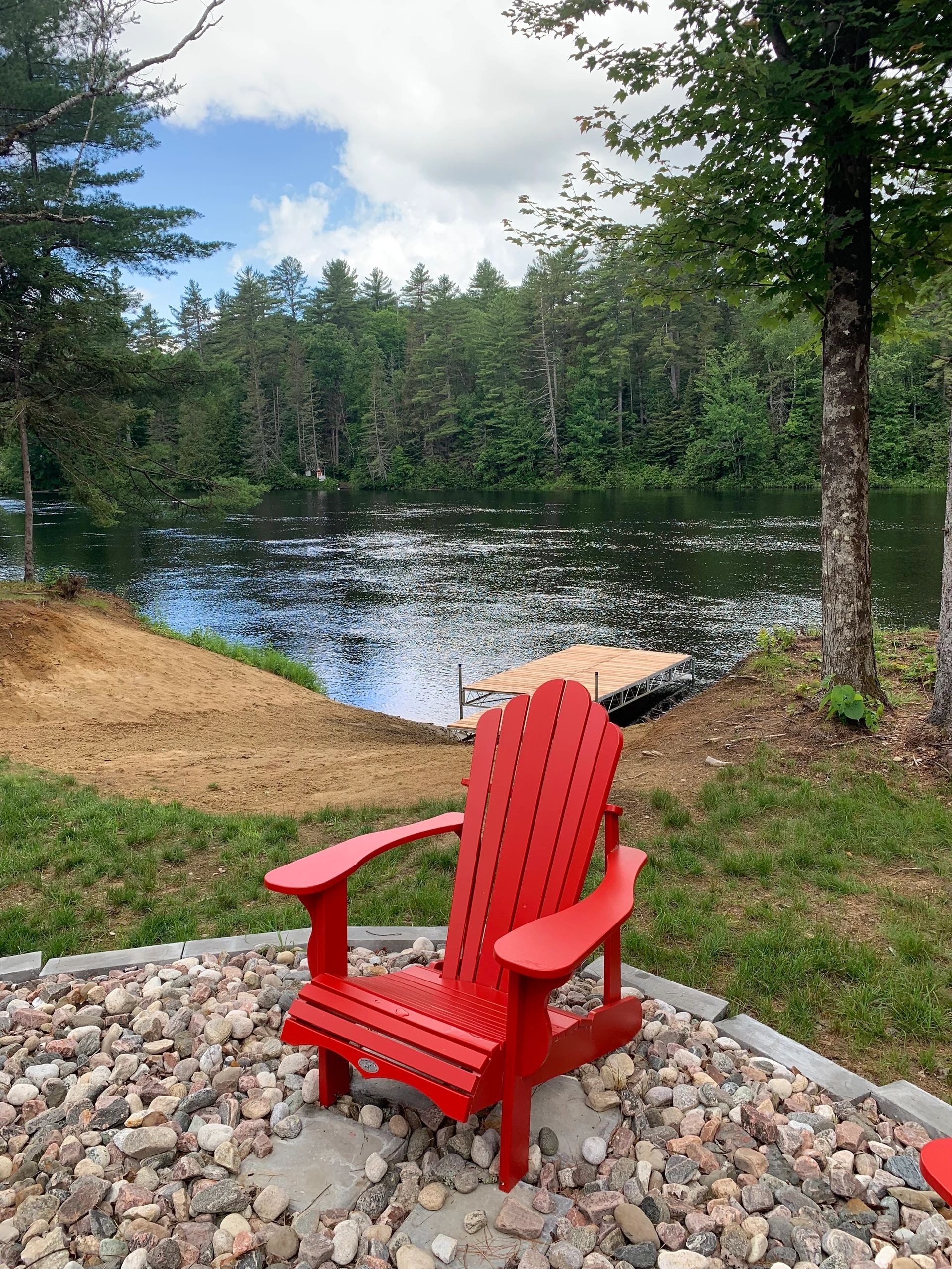 Red Adirondack chair on the beach by the lake
